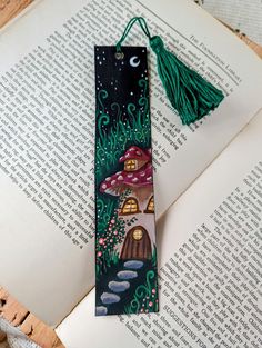 a bookmark with an image of a mushroom house on it and a green tassel