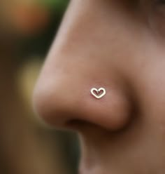 a close up of a person's nose with a small heart piercing on it