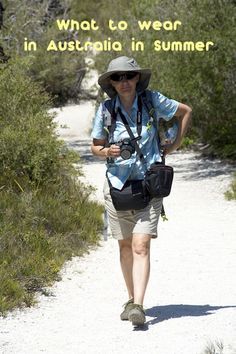 a woman walking down a dirt road with a camera on her shoulder and the words, what to wear in australia in summer