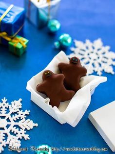 there are two cookies in the box on the table with snowflakes around it