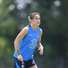 a female soccer player is running with the ball in her hand and she has tattoos on her arm