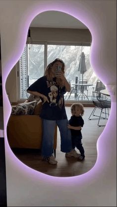 a woman taking a selfie in front of a mirror with a child standing next to her