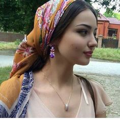 a woman with a scarf around her head wearing a necklace and earring on the neck