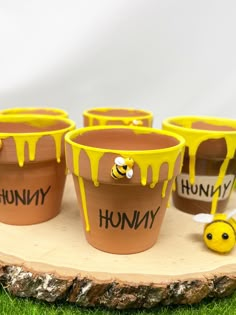 four flower pots with painted words on them sitting on top of a piece of wood