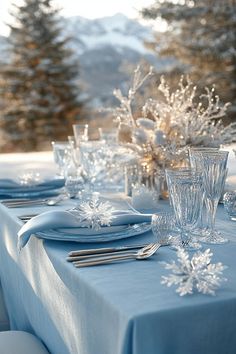 the table is set with silverware and blue linens for an elegant winter dinner