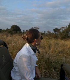 a woman sitting in the back of a vehicle on top of a grass covered field