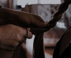 a woman is braiding her long hair with a pair of scissors and another person's hand