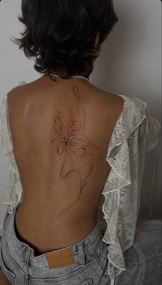 the back of a woman's body with a flower tattoo on it