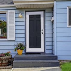 a blue house with white shutters and a black door on the front porch is shown