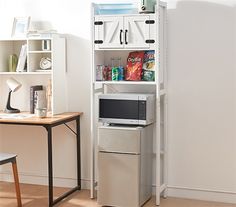 a microwave oven sitting on top of a white shelf next to a desk and chair