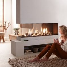 a woman sitting on the floor in front of a fireplace