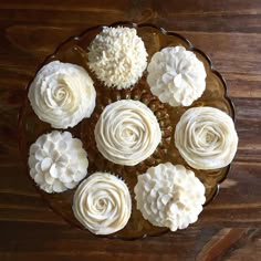 cupcakes with white frosting are arranged in a circle on a brown plate