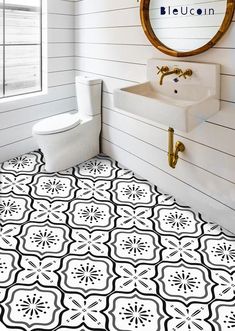 a bathroom with black and white tiles on the floor next to a sink, toilet and mirror