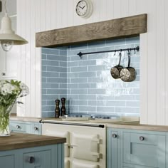 a kitchen with blue and white tiles on the backsplash, pot racks hanging over the sink