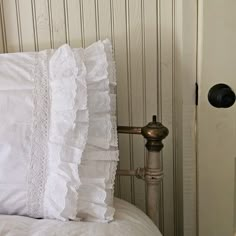 a white pillow sitting on top of a bed next to a metal faucet