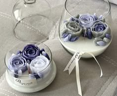 two glass bowls with flowers in them on a table