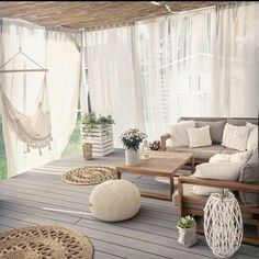 an outdoor living area with hammock and pillows on the floor, potted plants