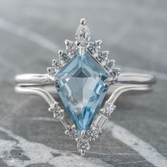 an aqua blue topazte and diamond ring on a table with other jewelry items