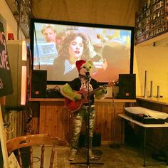 a man playing guitar in front of a large screen