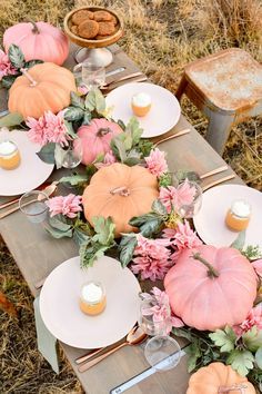 the table is set with pumpkins and flowers