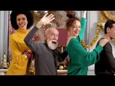 three women and one man are dancing in front of christmas decorations with their hands up