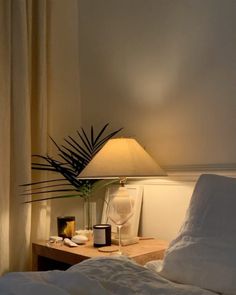 a bed with white sheets and a lamp next to it on top of a wooden table