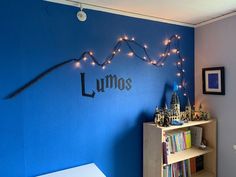 a room with blue walls and string lights on the wall, along with bookshelves