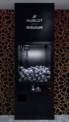 an image of a machine that is in front of a wall with black and orange designs