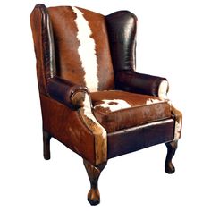 a brown and white chair sitting on top of a hard wood leg rest with cow hide upholster