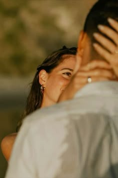 a man and woman standing next to each other with their hands covering their faces in front of them