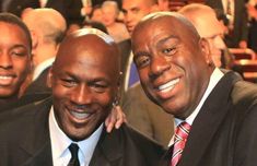 two men in suits and ties posing for a photo with one man smiling at the camera