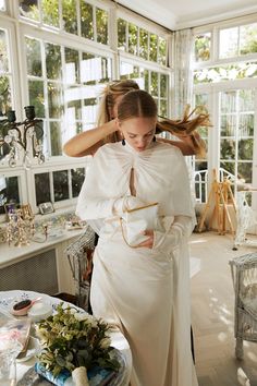 a woman in a white dress standing next to a table