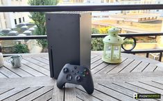 a video game controller sitting on top of a wooden table next to a metal box