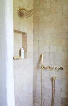 a bathroom with a shower head and hand held shower faucet in the corner