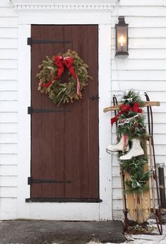 a sled and wreath on the front door of a white house