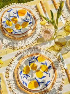 two plates with blue and yellow designs on them sitting on a tablecloth covered table