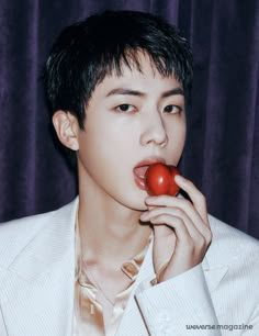 a man in a white suit is holding a tomato