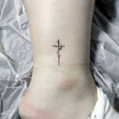 a small cross tattoo on the ankle