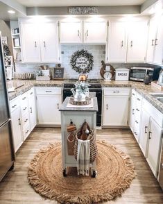 a kitchen with white cabinets and an island in front of the stove, surrounded by rugs