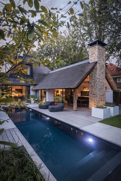 a house with a swimming pool in front of it and an outdoor fireplace on the side