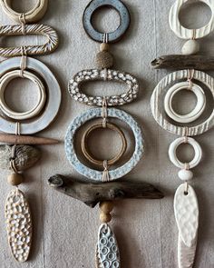 several different types of jewelry hanging on a white tablecloth covered wall with beads, rings and other items