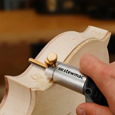 a person is holding a woodworking tool in their left hand and working on a piece of wood