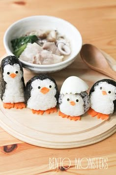 four little penguins are made out of rice and sit in front of a bowl of soup