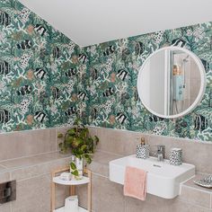 a bathroom with floral wallpaper and a mirror on the wall next to a sink