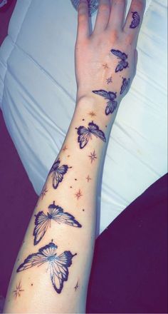 a woman's arm with butterflies on it and stars in the sky above her