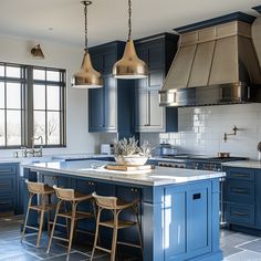 a kitchen with blue cabinets and white counter tops, two stools in front of the island