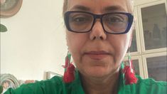 an older woman wearing glasses and a green shirt with red tassels on her ears