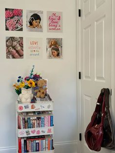 a white book shelf with pictures on the wall and flowers in vases next to it