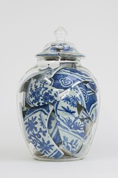 a blue and white glass jar with an ornate design on the lid is shown in front of a white background