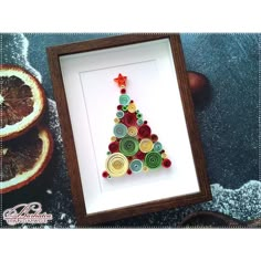 a christmas tree made out of buttons in a shadow box with an ornament